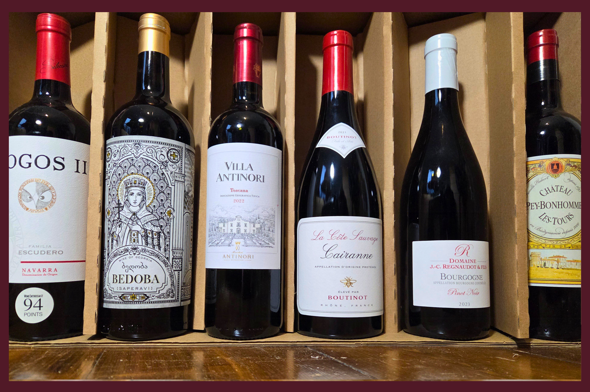 Collection of wine bottles in a wooden box with visible labels.