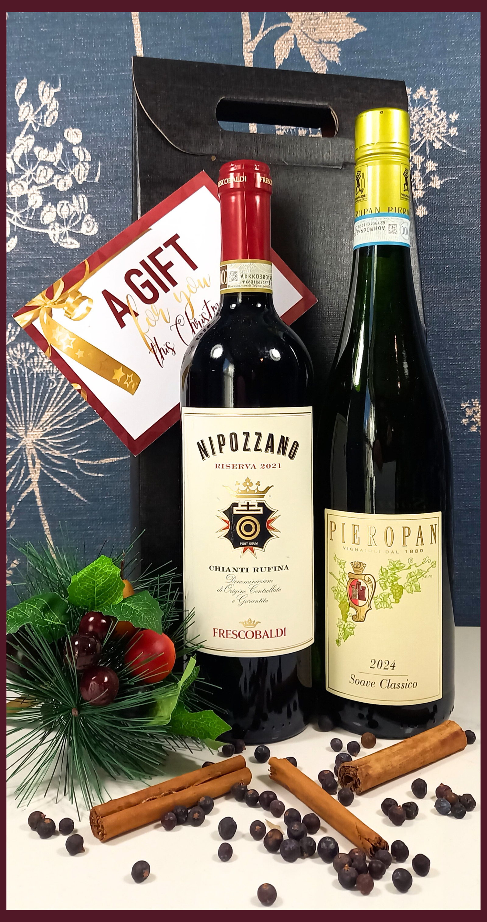 Two wine bottles in a gift box with a decorative card on a floral background