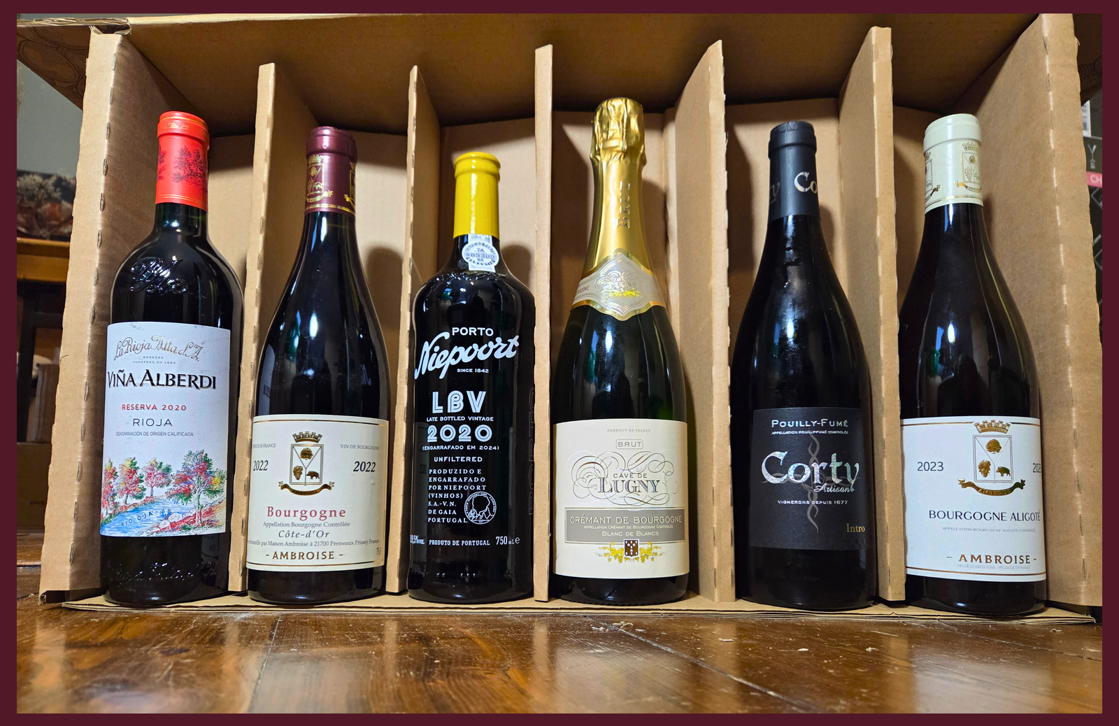 Collection of wine bottles in a wooden box on a wooden surface