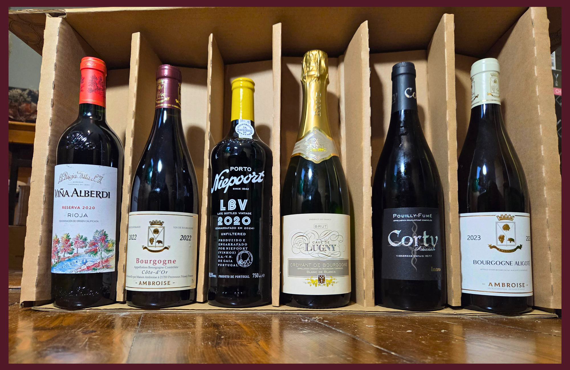 Collection of wine bottles in a wooden box on a wooden surface